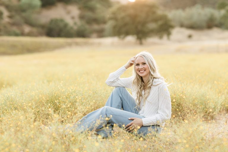Blonde senior girl sitting in a field of yellow flowers in San Luis Obispo by Elizabeth Hay Photography