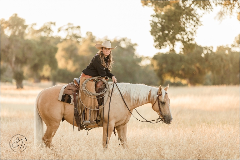 cowgirl sitting on a palomino horse in a golden field during an equine photography workshop
