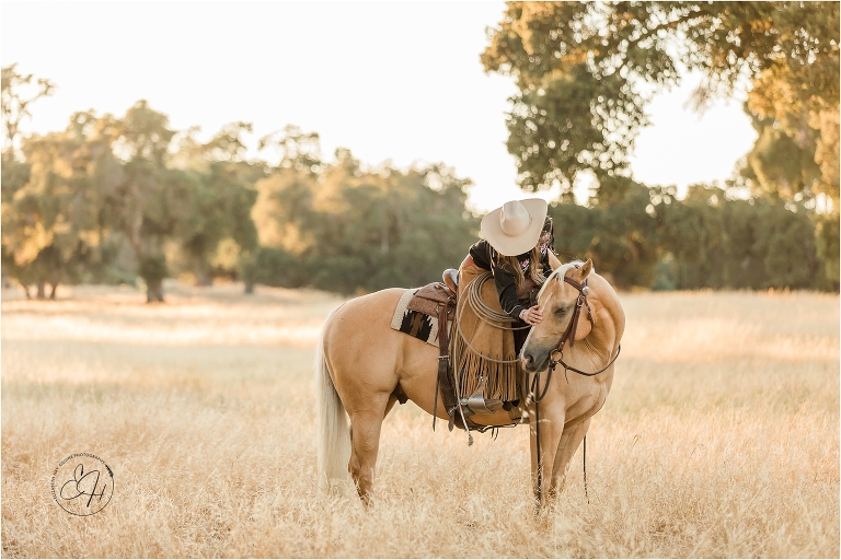 cowgirl petting a palomino horse in a golden field during an equine photography workshop in California