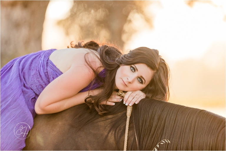woman wearing a purple parachute dress laying down on a dark gelding at Oyster Ridge wedding venue during an equine photography workshop