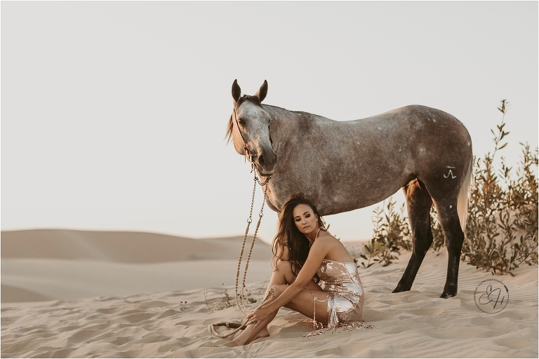 woman sitting with horse at a high fashion equine shoot at the Pismo Beach Dunes by Elizabeth Hay Photography