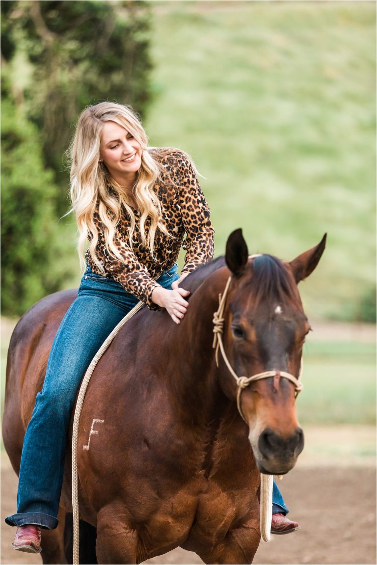 Woman sitting on horse and petting him during a Morro Bay Equine Photography session by Elizabeth Hay Photography