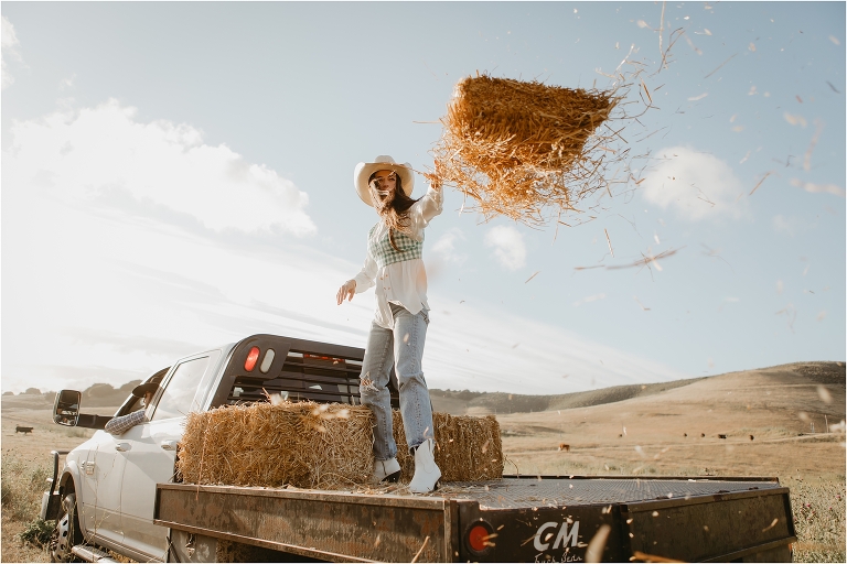 Lindsay Branquinho throwing a hay bale off the back of a feed truck driving by her husband Luke Branquinho