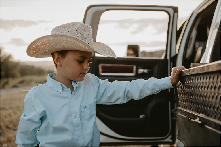young cowboy inspects truck bed by Elizabeth Hay Photography 