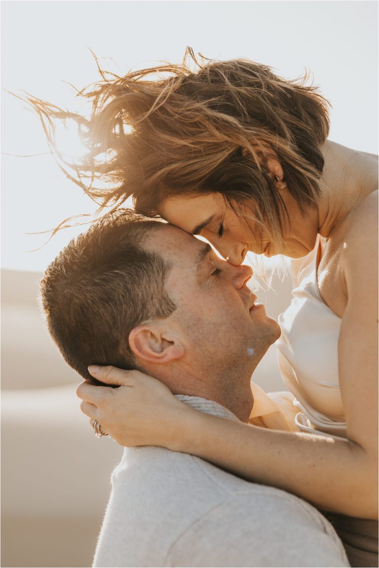 couple with heads together on beach dunes in Pismo Beach California by Elizabeth Hay Photography