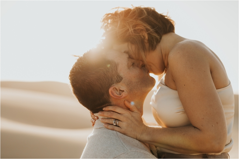 couple kissing on beach dunes in Pismo Beach California by Elizabeth Hay Photography