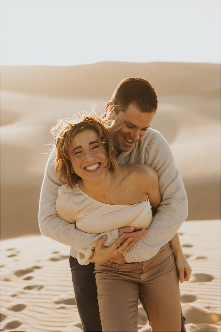 couple hugging on beach dunes in Pismo Beach California by Elizabeth Hay Photography