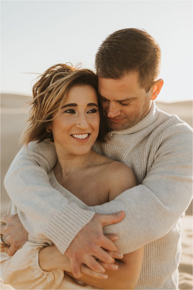 couple hugging on beach dunes in Pismo Beach California by Elizabeth Hay Photography
