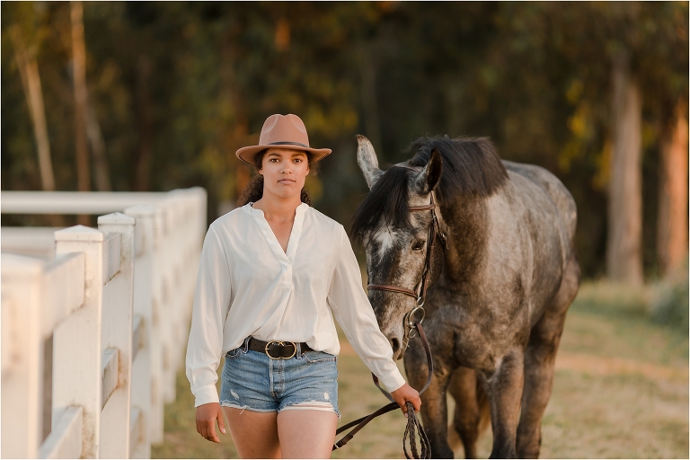 Taylor and her grey show jumper gelding Yonder standing near horse jumps by California Equine Photographer, Elizabeth Hay Photography