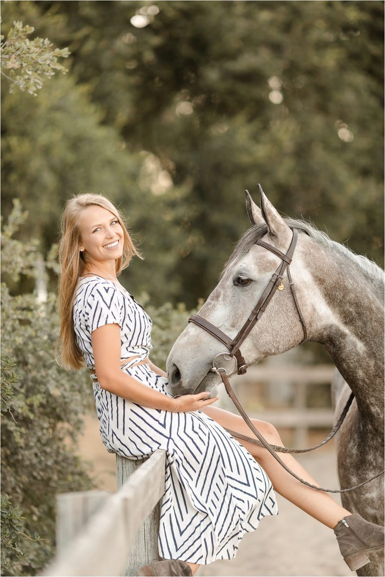 blonde girl sitting on fence with grey gelding by California Equine Photographer Elizabeth Hay Photography at Oak Park Equestrian Center. 
