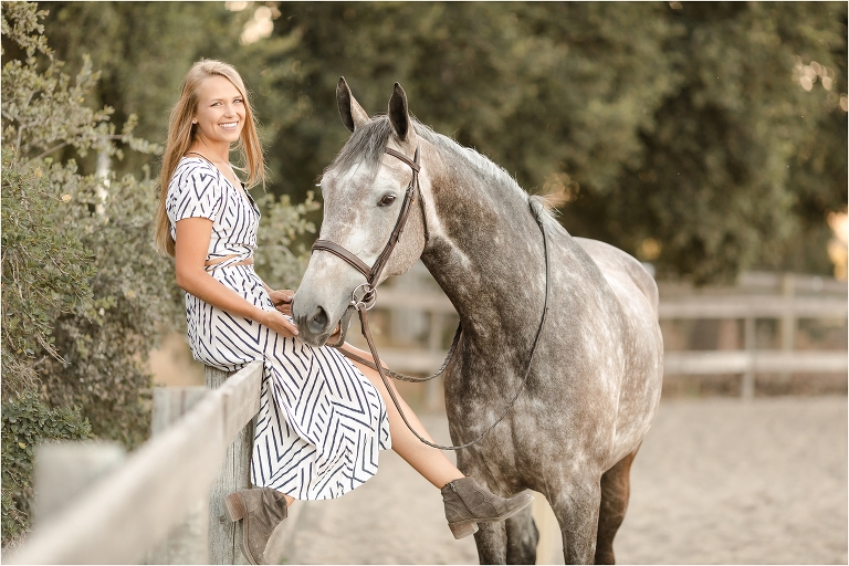 blonde girl sitting on arena fence with dapple grey gelding by California Equine Photographer Elizabeth Hay Photography at Oak Park Equestrian Center. 
