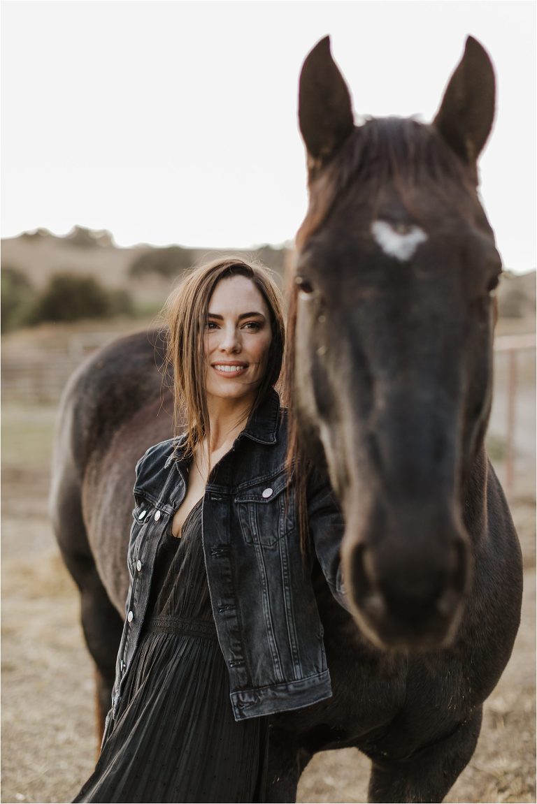 Lindsay Branquinho standing with a black mare wearing western fashion by California Equine Photographer Elizabeth Hay Photography. 