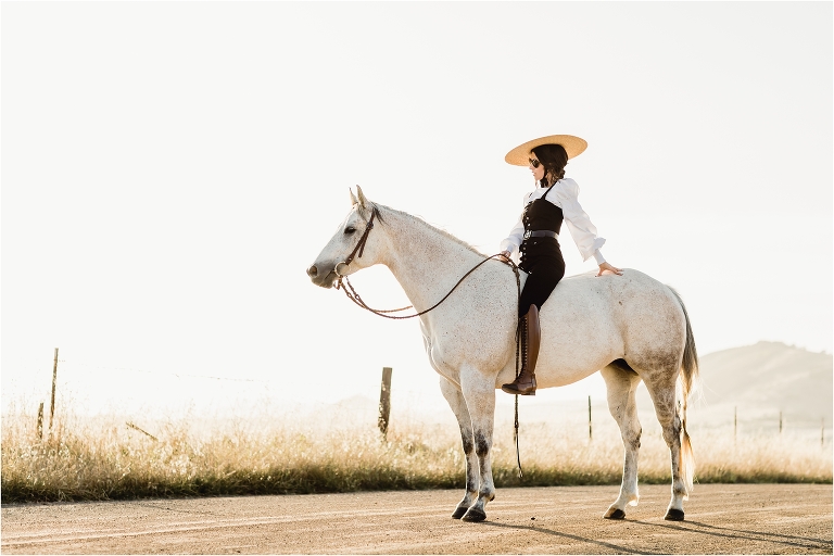 woman wearing black overalls and riding boots with grey horse on county back road by California Equine Photographer Elizabeth Hay Photography