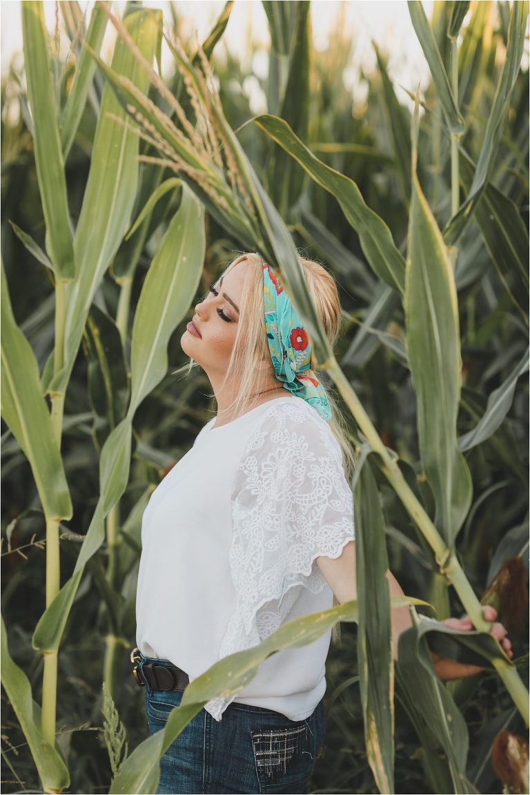 Blonde girl wearing sheer white top and teal tribal print wild rag in a corn field by California Equine Photographer Elizabeth Hay Photography.
