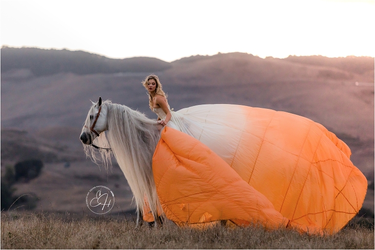 woman wearing orange parachute dress while riding an Andalusian stallion shot by California Equine Photographer Elizabeth Hay Photography. 