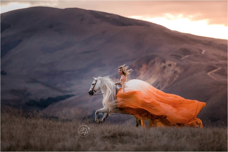 woman wearing orange and white parachute dress while riding an Andalusian stallion shot by California Equine Photographer Elizabeth Hay Photography. 