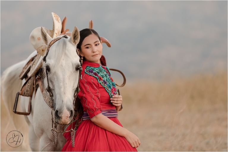 Escaramuza rider wearing traditional red dress and her horse by California Horse Photographer Elizabeth Hay Photography