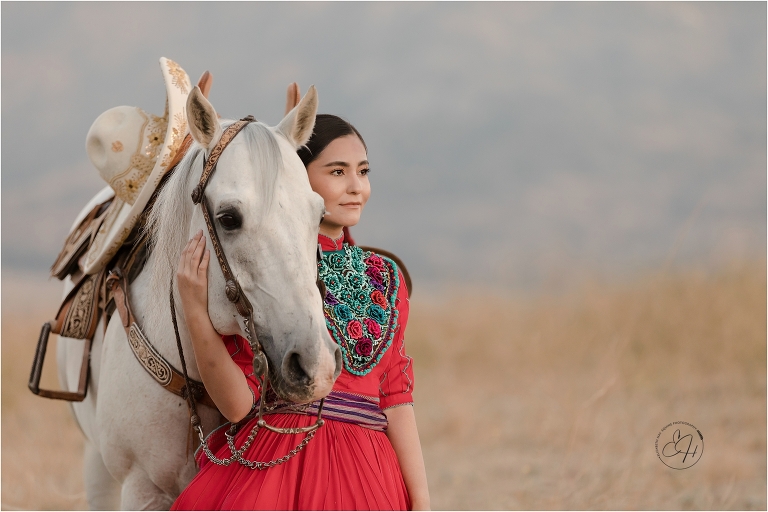 Escaramuza rider wearing traditional red dress and her grey horse by California Horse Photographer Elizabeth Hay Photography