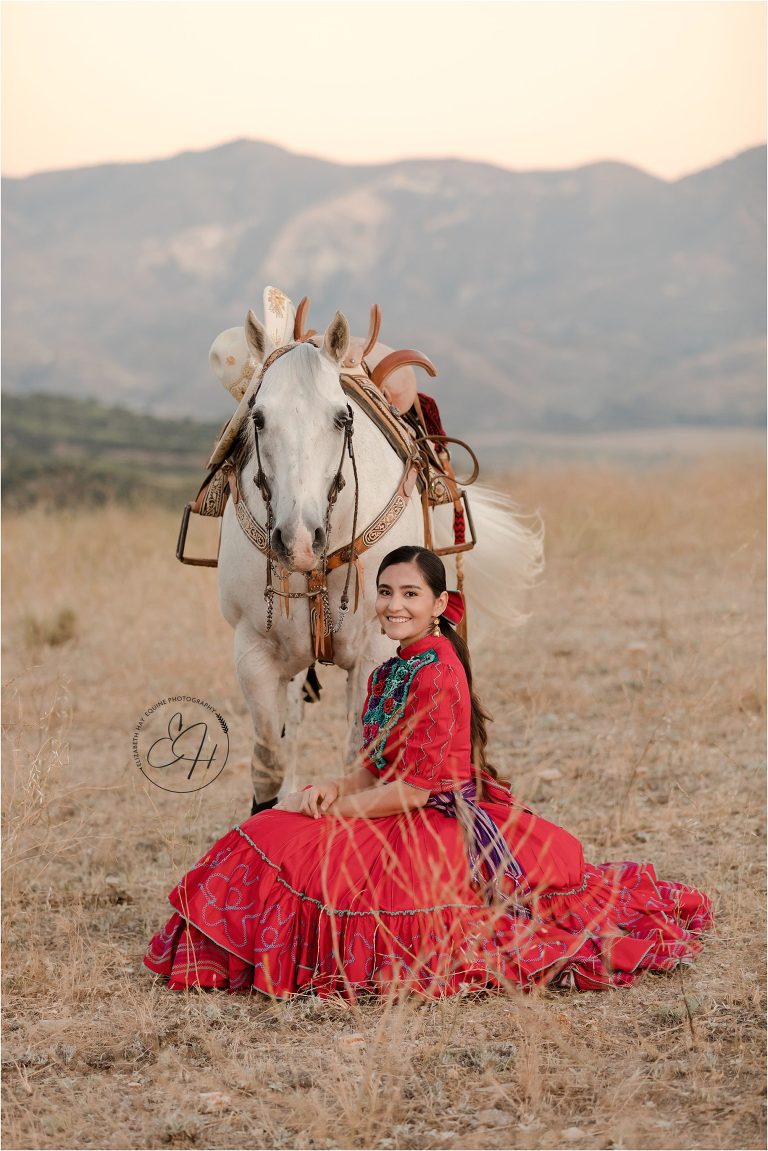 Escaramuza rider wearing traditional red dress and her grey gelding by California Horse Photographer Elizabeth Hay Photography
