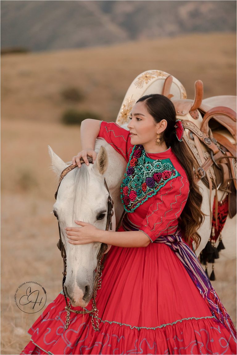 Escaramuza rider wearing traditional red dress with her horse by California Horse Photographer Elizabeth Hay Photography