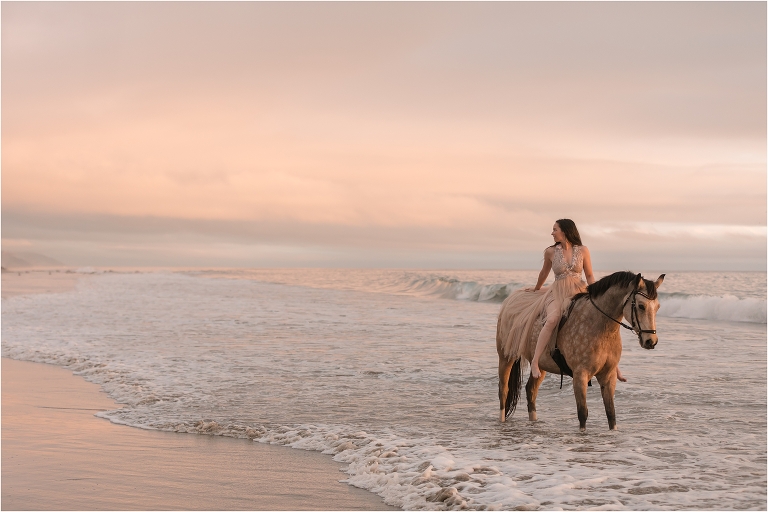 Horse and rider standing in beach waves at sunset by California Equine Photographer Elizabeth Hay Photography